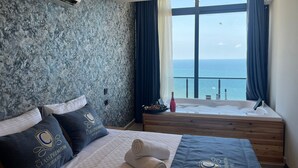 A bedroom with a bed, a bathtub, and a view of the sea. - Class Premium Hotel (Erdemli)