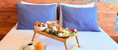A hotel room with a bed, two pillows, a tray with breakfast, a cup of coffee, and a glass of orange juice.