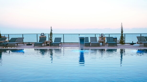 A poolside area with lounge chairs and a view of the sea. - Class Premium Hotel (Erdemli)