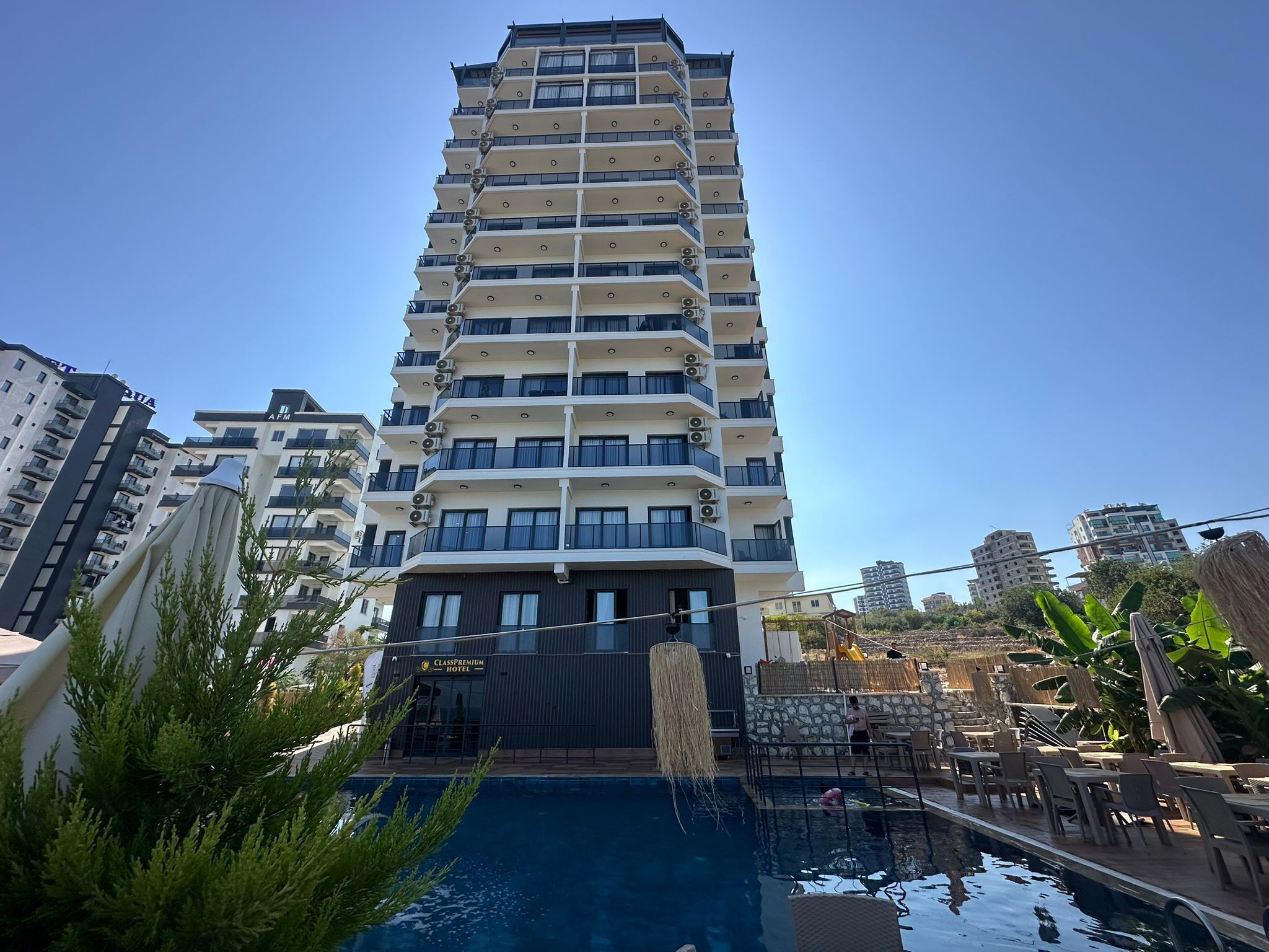 A multi-story hotel with a swimming pool and outdoor seating area.