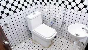 Baño con inodoro, lavabo y ducha. Las paredes están cubiertas de un patrón blanco y negro.