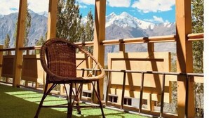 Una pérgola de madera con una silla de mimbre, con vistas a un paisaje montañoso.