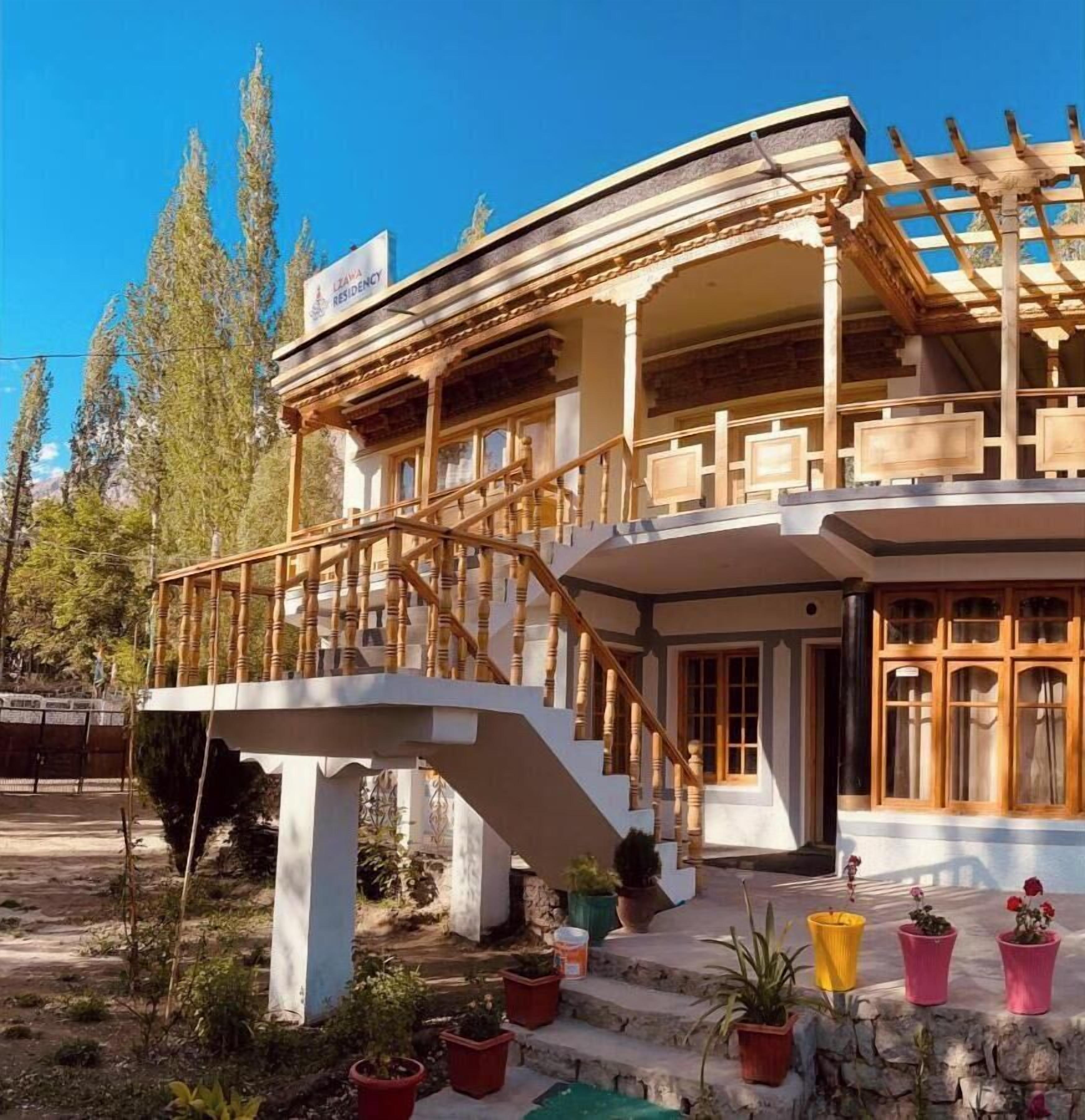 A two-story building with a wooden balcony and a staircase leading to the entrance.
