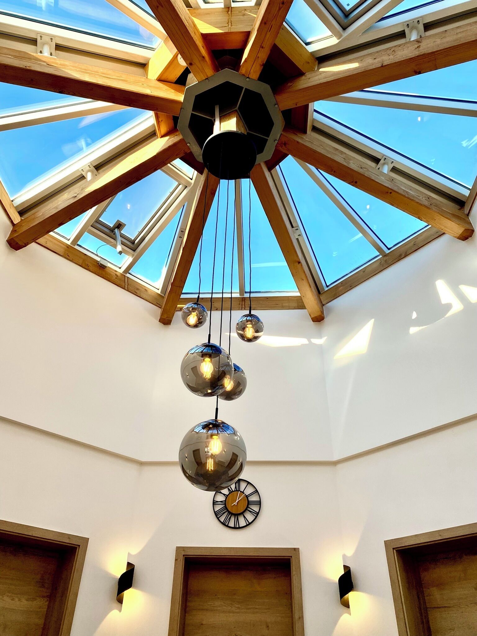A room with a skylight, wooden beams, and hanging spherical light fixtures.