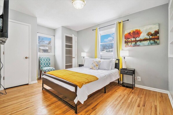 A bedroom with a bed, bedside tables, a wardrobe, and a painting on the wall.