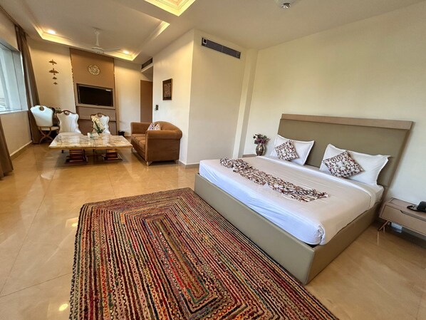 Una habitación de hotel con cama, sofá, mesa de comedor y televisión.