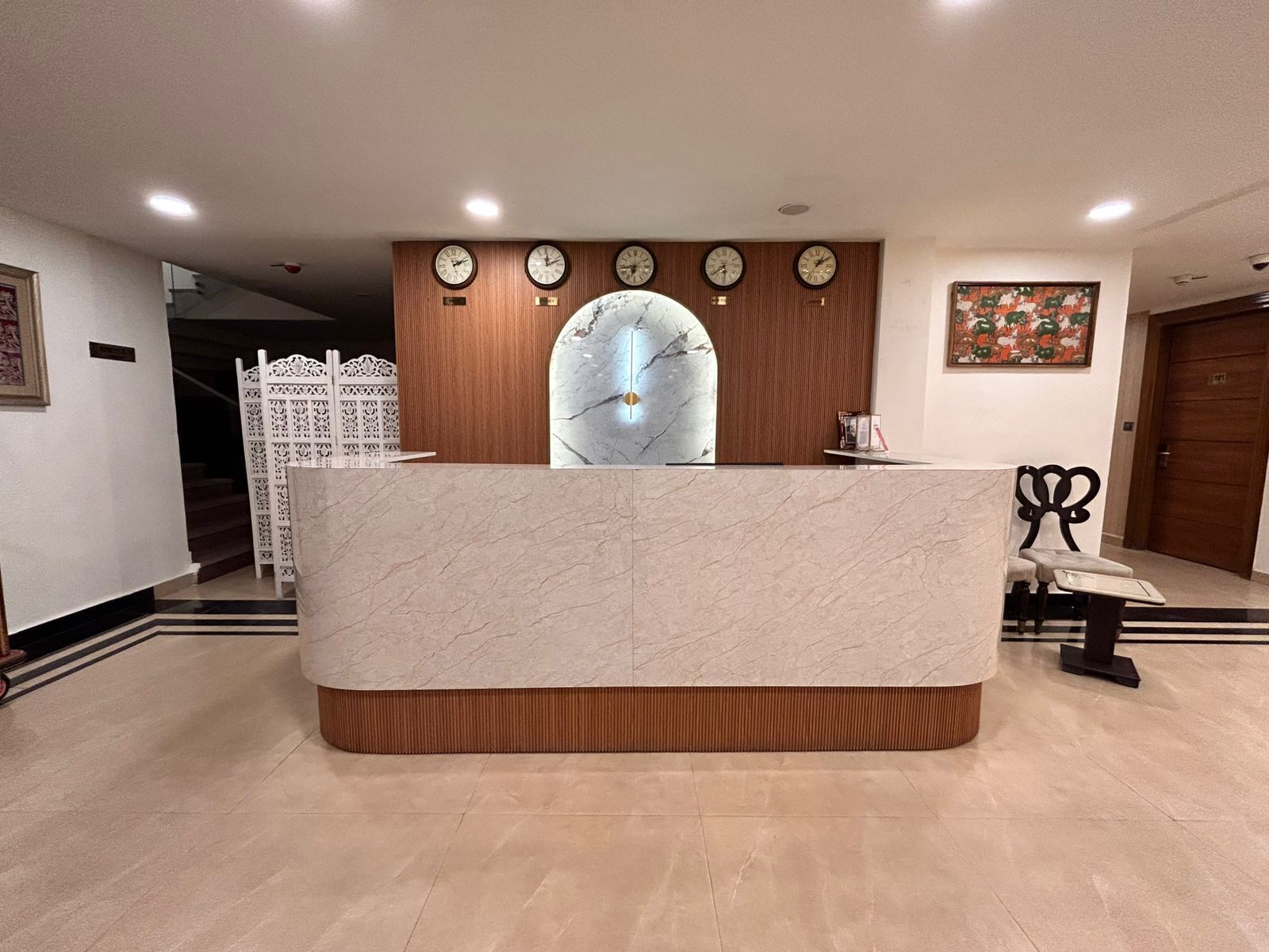 A reception desk with a marble top, wooden paneling, and clocks above it.