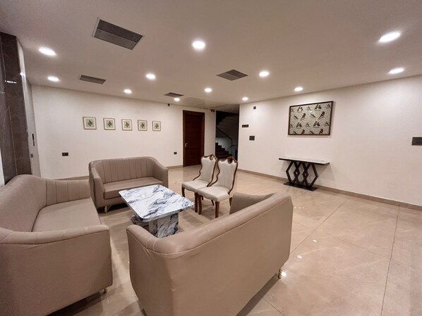 Una habitación amplia con sofá, una silla, una mesa de mármol y una obra de arte en la pared.