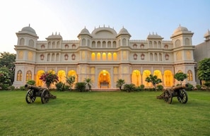 A large, ornate building with multiple domes and arched windows, surrounded by a well-maintained lawn and two cannons. - Kairvi Fort Resort Moradabad (Moradabad)