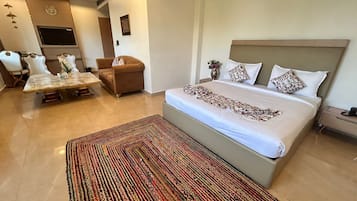 A bedroom with a bed, a sofa, a dining table, and a TV.