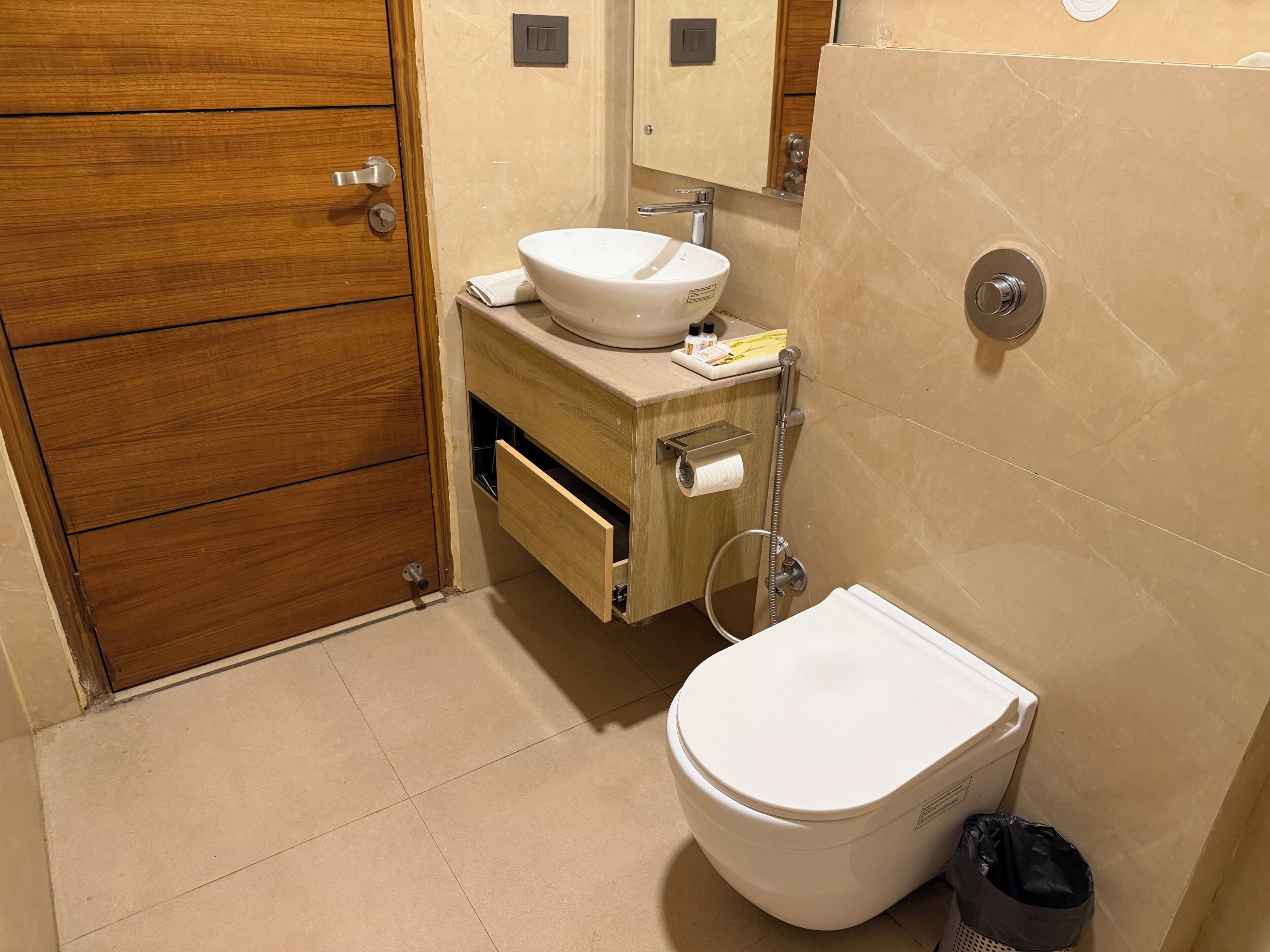 Une salle de bain avec un meuble-lavabo en bois, un lavabo blanc, des toilettes et une douche.