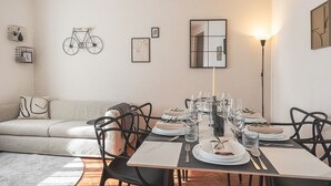Un coin repas avec une table dressée pour quatre personnes, entouré de chaises noires, d’un canapé et d’un vélo fixé au mur.