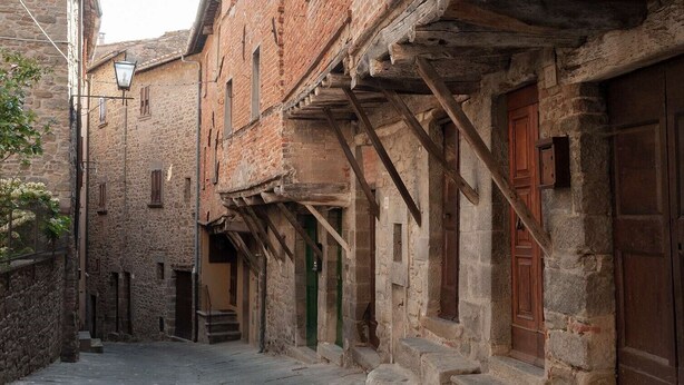 Une rue étroite bordée de bâtiments en pierre, de poutres en bois et de portes en bois d’époque.