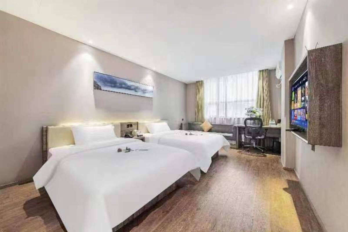 A hotel room with two beds, a desk, and a television.