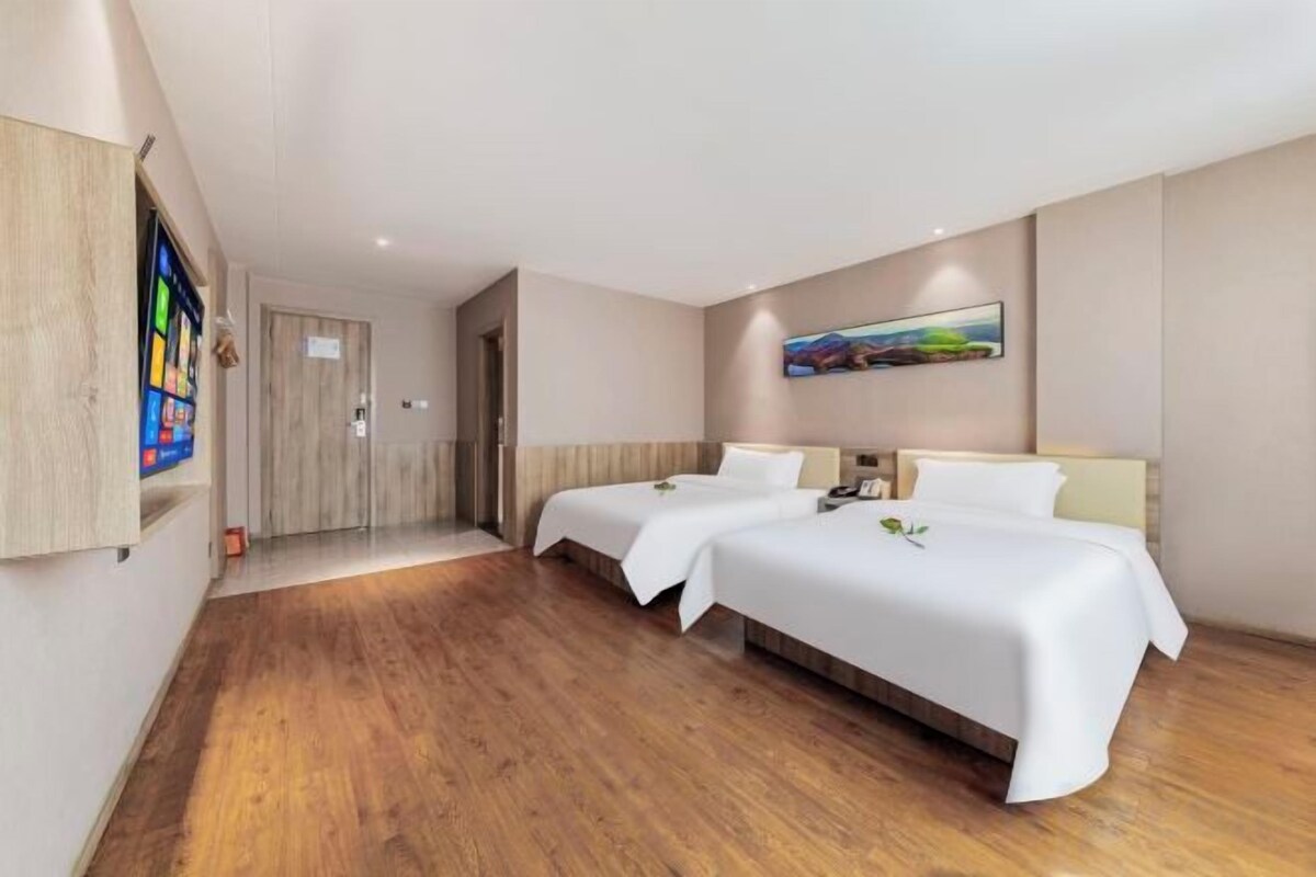 A hotel room with two beds, a television, and a painting on the wall.