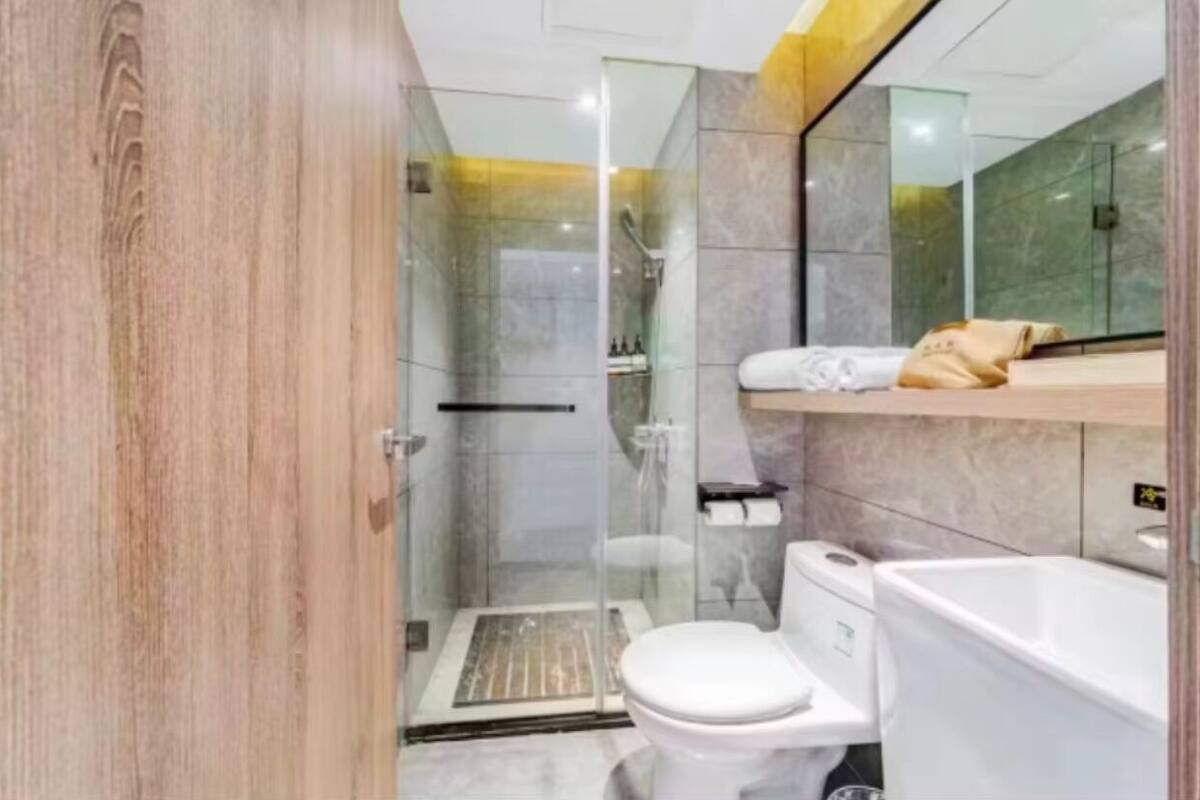 A modern bathroom with a glass-enclosed shower, a toilet, and a bathtub.