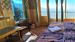 A room with a bed, a bench, and a view of mountains through large windows. - Hotel HILL Mount View Dalhousie Chamba  (Dalhousie)