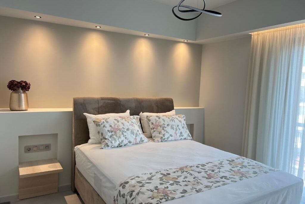 Quarto moderno com uma cama grande, mesa de cabeceira e prateleira na parede.