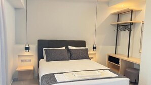 Ett modernt hotellrum med en stor säng, sängbord, en hylla på väggen och en klädstång.