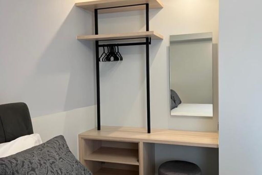Une chambre à coucher comprenant un lit, une table de chevet, un miroir et une bibliothèque intégrée.