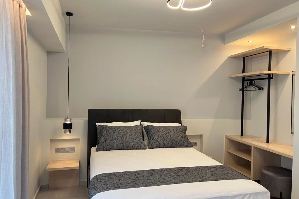 Um quarto moderno com cama, mesas de cabeceira, luminária pendente e estantes embutidas.