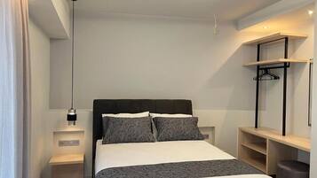 Um quarto moderno com cama, mesas de cabeceira, luminária pendente e estantes embutidas.