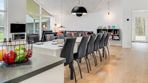 Ett modernt kök med en stor köksö, en matplats med stolar och en tv som är monterad på väggen.
