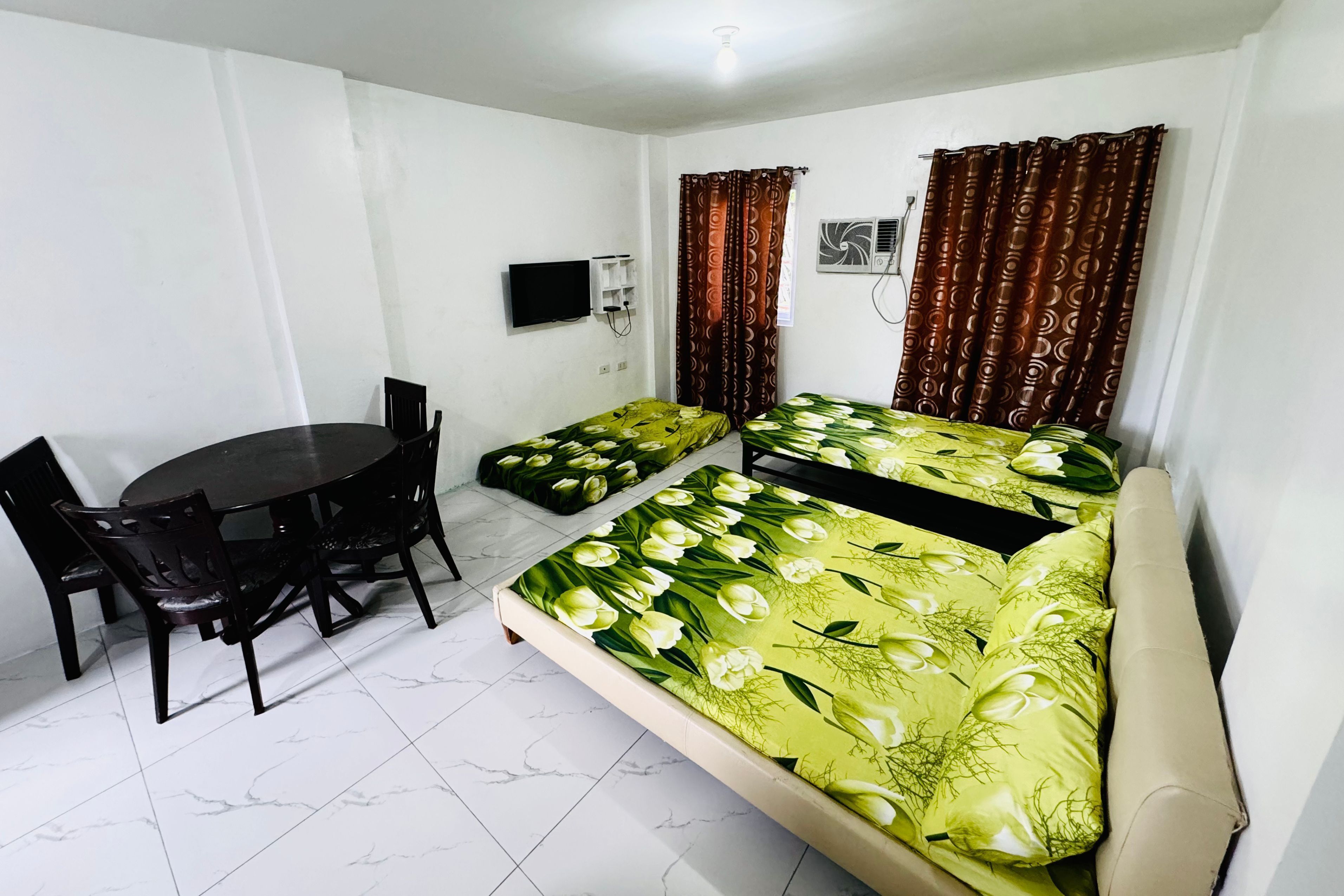 A room with two beds, a dining table, and chairs.