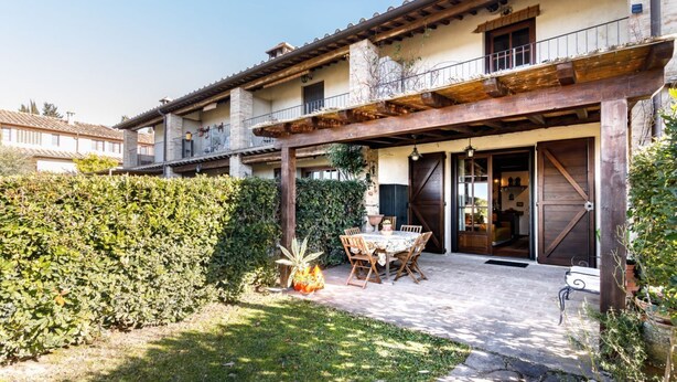 A courtyard with a table and chairs, a wooden pergola, and a hedge. - GuestHost - Nestled between the Crete Senesi and Chianti, this home offers a breathtaking view of the countryside and Siena, just a 10-minute drive away. Part of a renovated historic farmhouse, it is a well-furnished townhouse with a private garden and v (Castelnuovo Bardenga)