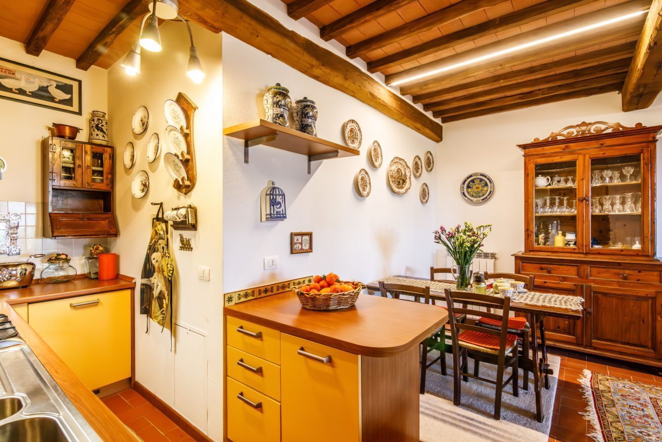 A kitchen with wooden cabinets, a dining table, and a fruit basket.