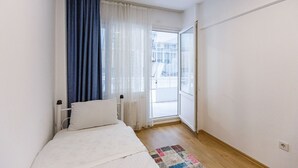 A small, bright room with a bed, a window with sheer curtains, and a view of the outside. - Charming 3-Bedroom Apartment in the Heart of Kadıköy (Kadıköy)