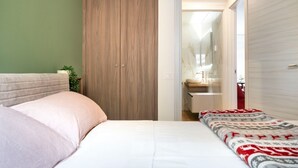 Un dormitorio con cama, armario y baño visible a través de una puerta abierta.