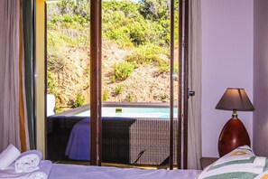 Ein Hotelzimmer mit Bett, Fenster mit Blick auf Pool und Grünflächen.