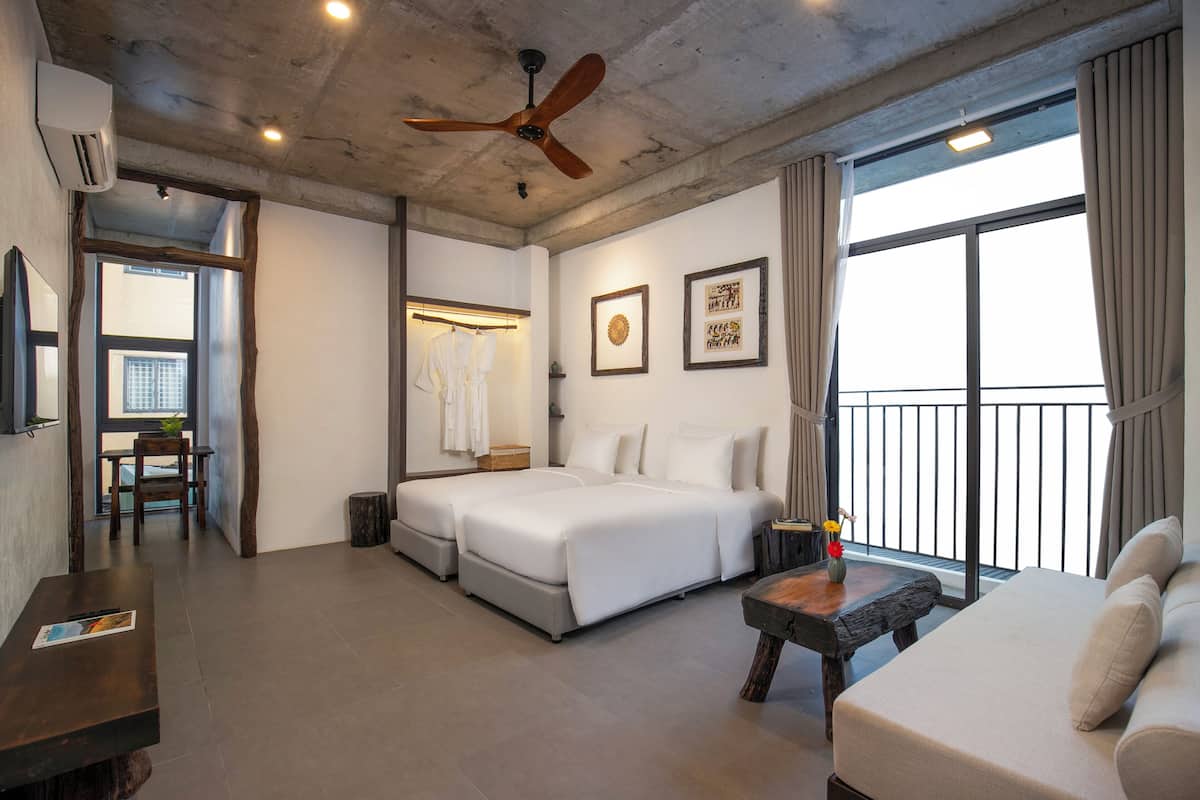 Una habitación de hotel moderna con una cama grande, un sofá, una mesa de comedor y un balcón con cortinas.