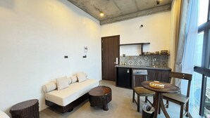 A compact living space with a sofa, a dining table, and a kitchenette. - Eco & Rustic Home Hoian (Da Nang)