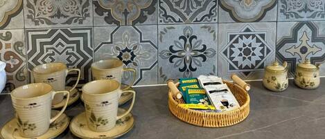 A kitchen counter with a stack of bowls, a tray of tea bags, and a basket of tea leaves.