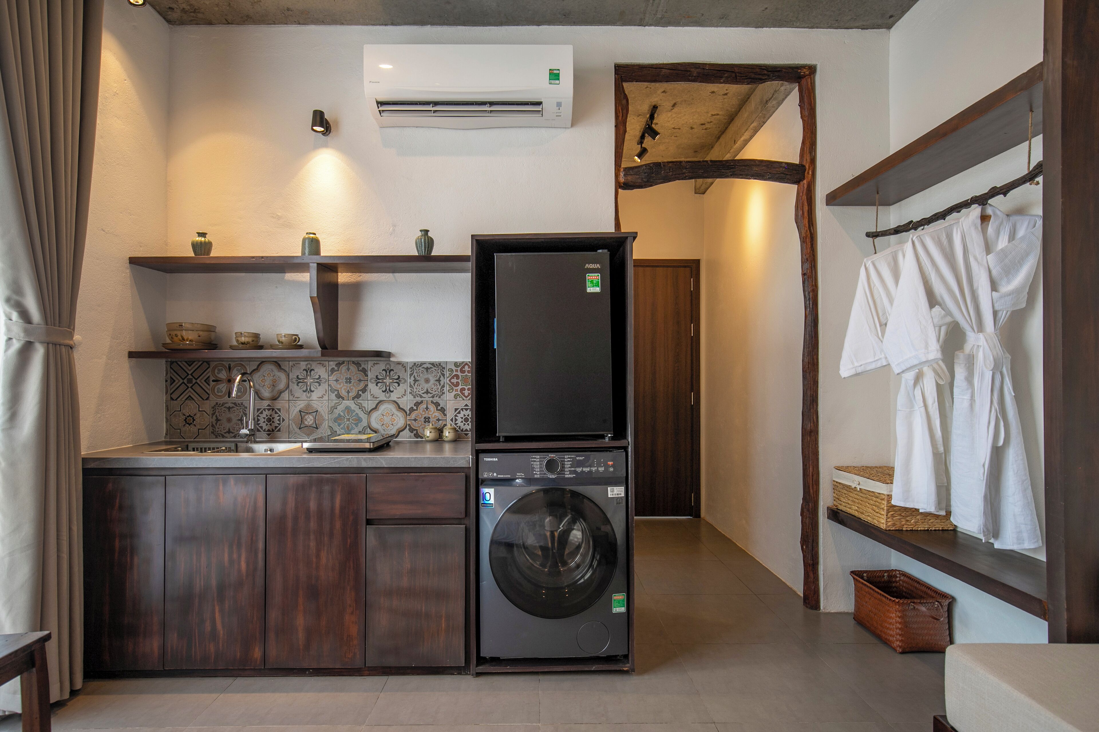 A compact kitchen with a built-in washer and dryer, wooden cabinets, and a tiled backsplash.