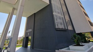 A modern building with a prominent vertical design, featuring a name plaque and a series of balconies.