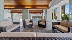 Un área de piscina interior moderna con mobiliario de mimbre y suelo de piedra.