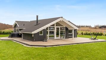 Een modern huis met een groot terras, een hottub en een ruime patio.