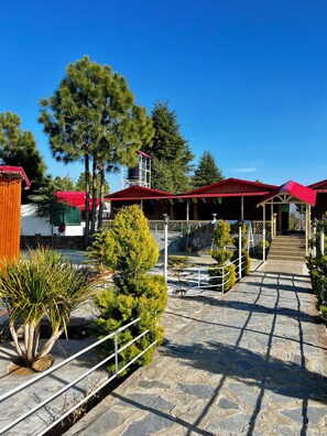Un patio con suelo de piedra, un área de estar techada y una torre de agua al fondo.