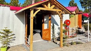 A rustic wooden building with a red roof, a wooden porch, and a stone-paved entrance. - THE CHAIL HEIGHTS HOTEL&RESORT (Shimla)