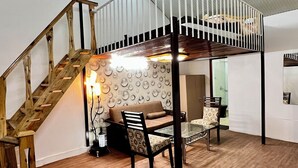 A loft-style room with a wooden staircase, a sofa, and a dining table. - THE CHAIL HEIGHTS HOTEL&RESORT (Shimla)