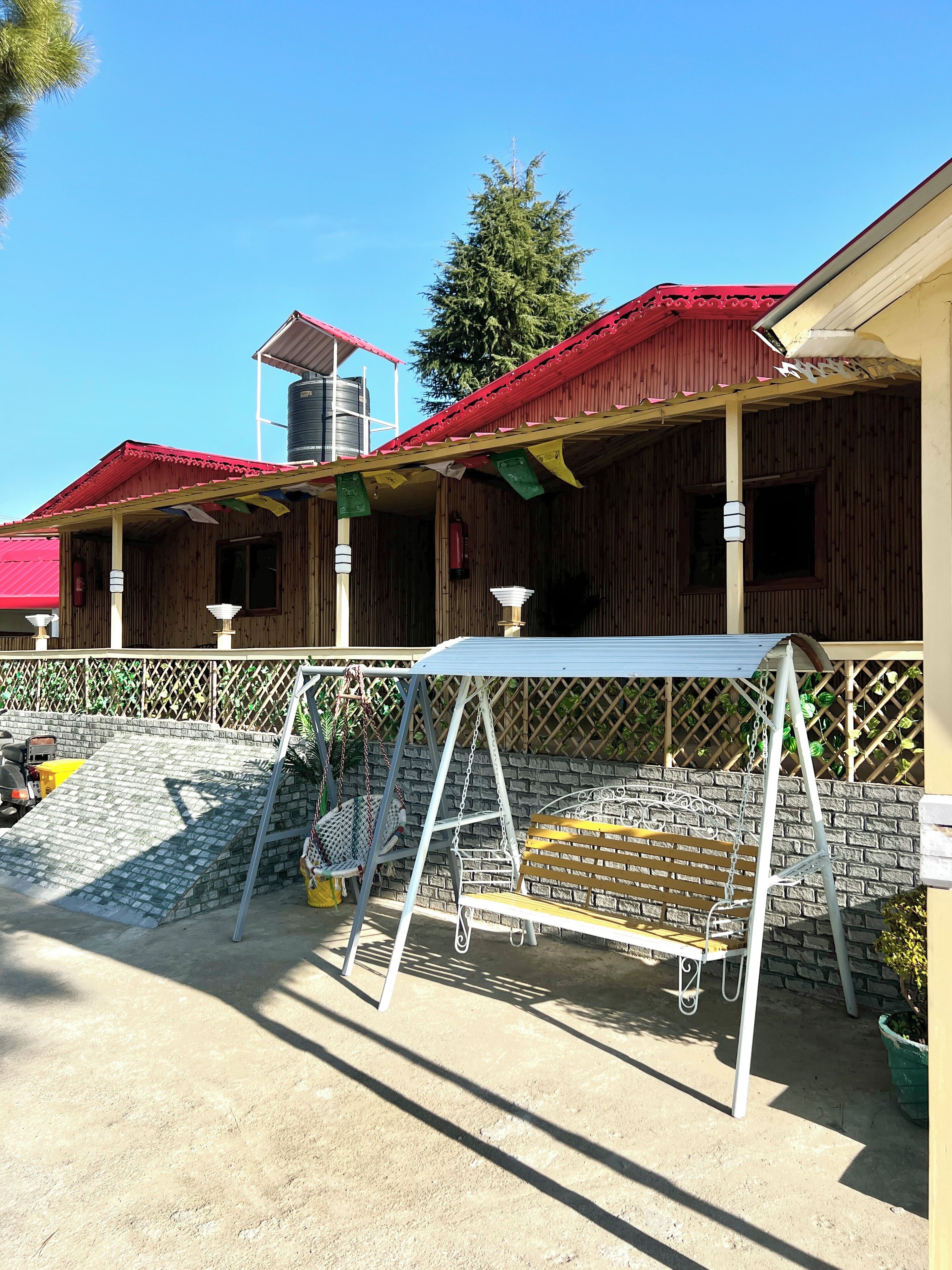 A wooden building with a red roof and a covered porch area.