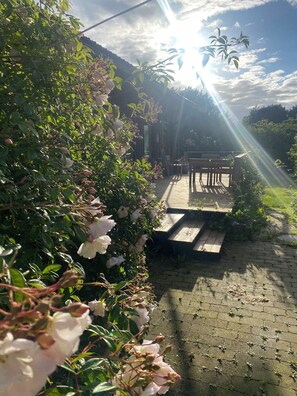 A garden with a wooden deck and a bench. - Romantic retreat close to the beach (Fårevejle)
