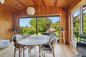 Un interior de madera con una mesa redonda, sillas y un gran ventanal.