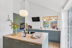 Una cocina moderna con una isla central, un televisor de pantalla plana y un ventanal con vistas al exterior.