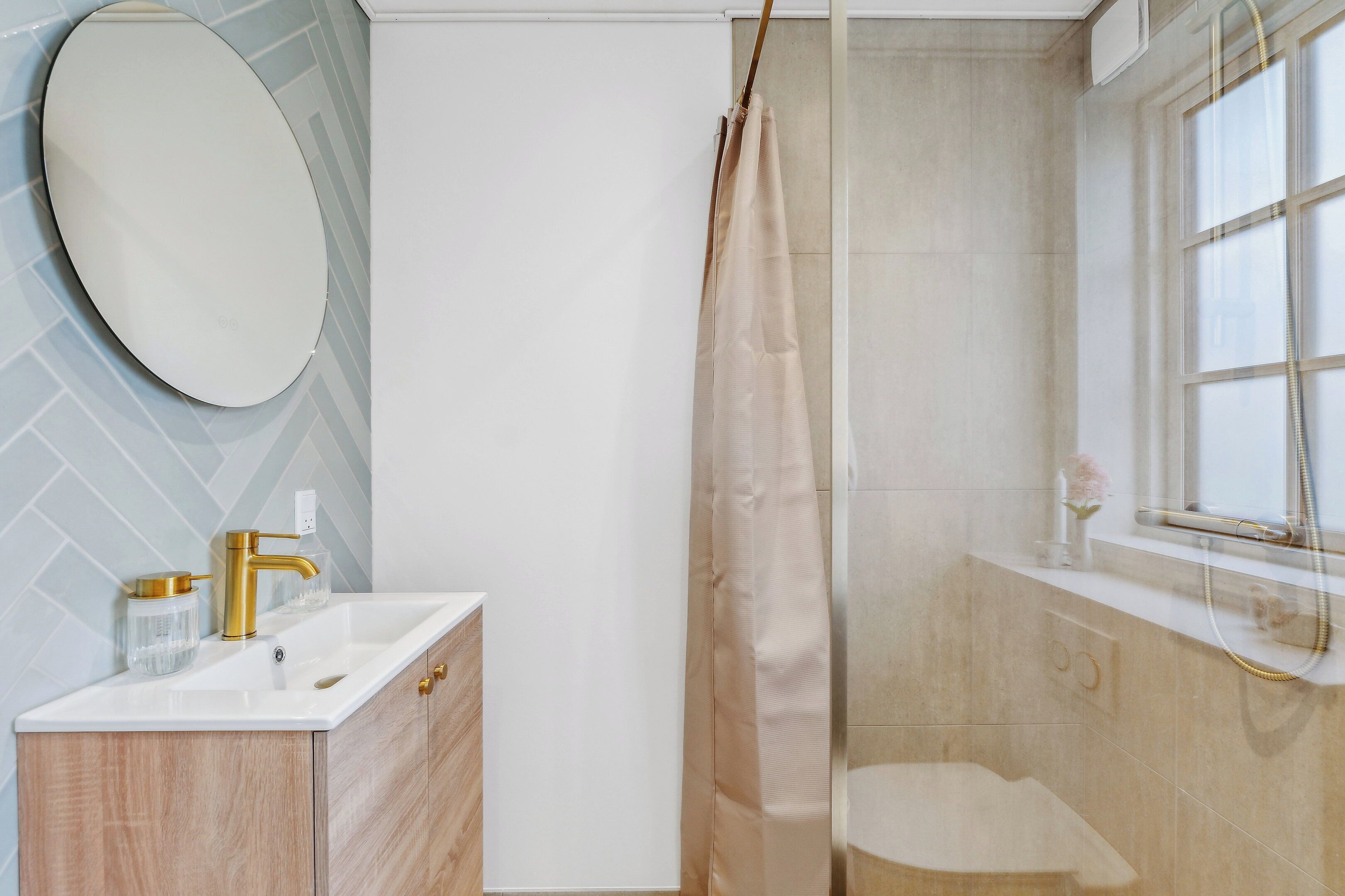 A bathroom with a white sink, gold faucet, and a shower curtain.