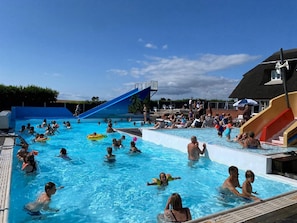 Une piscine avec des toboggans et un espace aménagé pour se détendre.