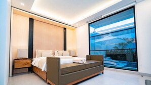 Un dormitorio moderno con una cama grande, mesitas de noche y vistas a una piscina a través de un amplio ventanal.